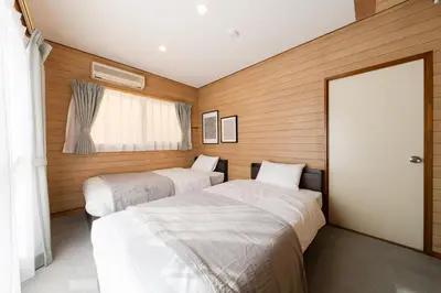 two beds in a room with wooden walls at Sora Den-en Stay in Tokyo