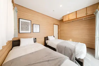 two beds in a room with wooden walls at Sora Den-en Stay in Tokyo