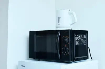 a black microwave sitting on top of a white cabinet at Kaminari INN in Tokyo
