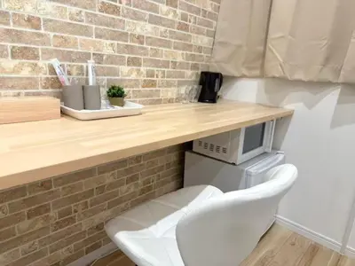 a white chair sitting under a wooden table with a microwave at \u967d\u6668\u30af\u30ea\u30b9\u30bf\u30eb\u4e09\u30ce\u8f2a\u65c5\u9928 in Tokyo