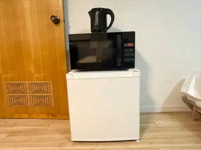 a microwave sitting on top of a white refrigerator at \u967d\u6668\u30af\u30ea\u30b9\u30bf\u30eb\u4e09\u30ce\u8f2a\u65c5\u9928 in Tokyo