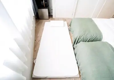 a white bed in a room with two green beds at Alice JueQie 1minute walk to Horikiri Station ,Super convenient transportation ,Direct access to Narita Airport , Drugstore, convenience store, and shopping center downstairs in Tokyo
