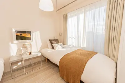 a white bedroom with a bed and a window at Mi-Hotel Ikebukuro in Tokyo