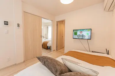 a bedroom with a bed and a tv on the wall at Mi-Hotel Ikebukuro in Tokyo