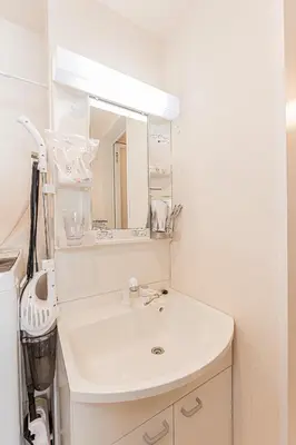 a white bathroom with a sink and a mirror at Mi-Hotel Ikebukuro in Tokyo