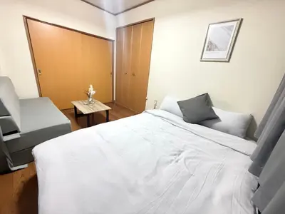 a bedroom with a large white bed and two chairs at Nogata RelaxingHome E2 in Tokyo