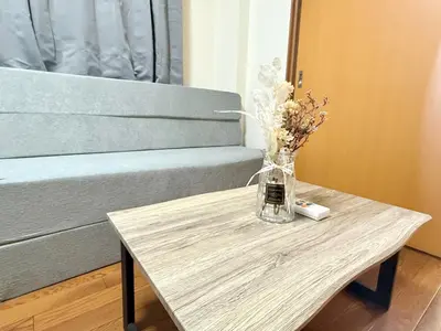 a vase of flowers on a table next to a bed at Nogata RelaxingHome E2 in Tokyo