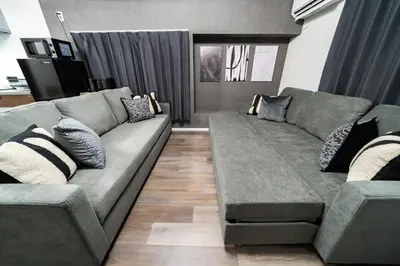 a living room with a large gray couch with pillows at 109, Nishiarai, \u897f\u65b0\u4e95 \u65b0\u898f\u30aa\u30fc\u30d7\u30f3, \u6771\u4eac\u89b3\u5149\u306b\u6700\u9069, 10\u540d\u69d8\u3054\u5229\u7528\u53ef\u80fd in Tokyo