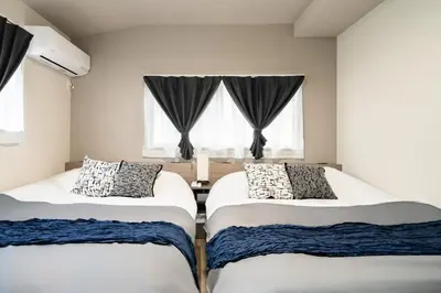 two beds in a room with two windows at 109, Nishiarai, \u897f\u65b0\u4e95 \u65b0\u898f\u30aa\u30fc\u30d7\u30f3, \u6771\u4eac\u89b3\u5149\u306b\u6700\u9069, 10\u540d\u69d8\u3054\u5229\u7528\u53ef\u80fd in Tokyo