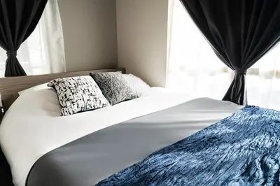 a white bed with two pillows and a window at 109, Nishiarai, \u897f\u65b0\u4e95 \u65b0\u898f\u30aa\u30fc\u30d7\u30f3, \u6771\u4eac\u89b3\u5149\u306b\u6700\u9069, 10\u540d\u69d8\u3054\u5229\u7528\u53ef\u80fd in Tokyo