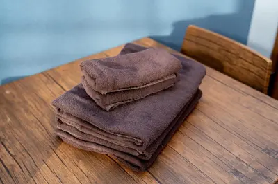 a pile of towels sitting on top of a wooden table at Opening January 2026 Just a five minute walk from Tabata Station on the Yamanote Line with direct access to Ikebukuro Shinjuku Shibuya and Ueno Comfortably sleeps 3 accommodates up to five guests in Tokyo