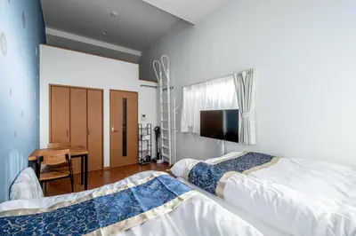 a bedroom with two beds and a desk and a television at Opening January 2026 Just a five minute walk from Tabata Station on the Yamanote Line with direct access to Ikebukuro Shinjuku Shibuya and Ueno Comfortably sleeps 3 accommodates up to five guests in Tokyo