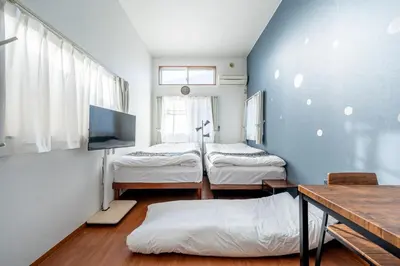 a room with two beds and a tv in it at Opening January 2026 Just a five minute walk from Tabata Station on the Yamanote Line with direct access to Ikebukuro Shinjuku Shibuya and Ueno Comfortably sleeps 3 accommodates up to five guests in Tokyo