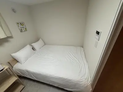 a small bedroom with a white bed in it at \u3055\u304f\u3089\u65c5\u9928 \u9ad8\u5186\u5bfa\u5317\u5343\u5229\u4f11 \uff42102\u53f7\u5ba4 in Tokyo