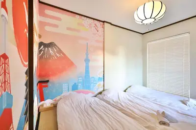 a bedroom with a bed and a wall with a mural at \u30a8\u30de\u30fc\u30ec\u6771\u5c0f\u5ca9201 \u5c0f\u5ca9\u99c5\u5f92\u6b695\u5206 \u6700\u59279\u540d \u548c\u5ba4\u7573 in Tokyo