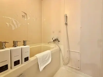a bathroom with a tub and a shower with a mirror at \u30a8\u30de\u30fc\u30ec\u6771\u5c0f\u5ca9101 \u5c0f\u5ca9\u99c5\u5f92\u6b695\u5206 \u6700\u59277\u540d \u548c\u5ba4\u7573 in Tokyo