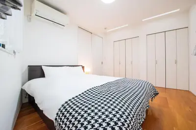 a bedroom with a bed with a black and white blanket at Hatagaya Honmachi house \u6da9\u8c37-SY0488 in Tokyo