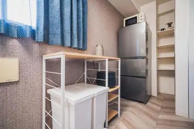 a small kitchen with a refrigerator and a shelf at Svalley YIG stay 401 in Tokyo