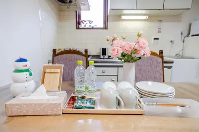 a kitchen table with a vase of flowers and milk bottles at 203 Room, a 6-minute walk from Tokyo Koiwa Station Direct connected to Shinjuku and Akihabara Stations Comfortable one-bedroom apartment with separate wet and dry areas in Tokyo