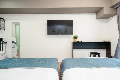 two beds in a room with a tv on the wall at Hotel SHINJYUKU in Tokyo