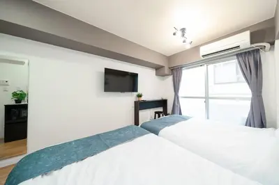 a bedroom with two beds and a flat screen tv at Hotel SHINJYUKU in Tokyo