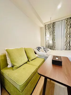 a living room with a green couch and a bed at jlb\u30b0\u30e9\u30f3\u30a8\u30af\u30ea\u30e5\u521d\u53f0 101 in Tokyo