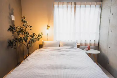 a bedroom with a large white bed with a window at Omotenashi HOTEL FamilyStay in Tokyo