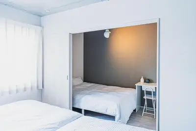 a mirror in a bedroom with a bed and a desk at Omotenashi HOTEL FamilyStay in Tokyo