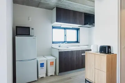 a small kitchen with a refrigerator and a sink at Omotenashi HOTEL FamilyStay in Tokyo
