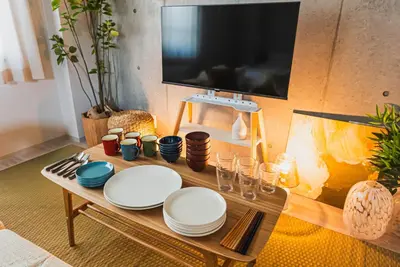 a table with plates and a flat screen tv at Omotenashi HOTEL FamilyStay in Tokyo
