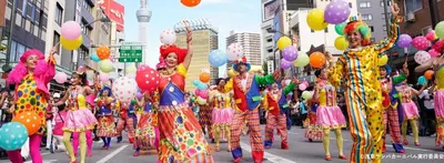 a group of people in colorful costumes walking down a street with balloons at Sunbright Asakusa 101 in Tokyo