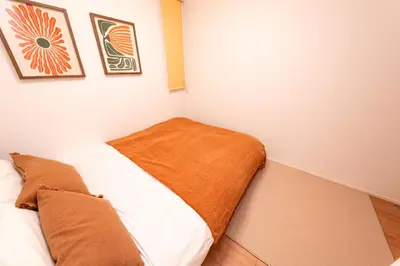 a bedroom with a bed with an orange blanket at Deload Hotel \u6771\u4eac\u3059\u307f\u3060 in Tokyo