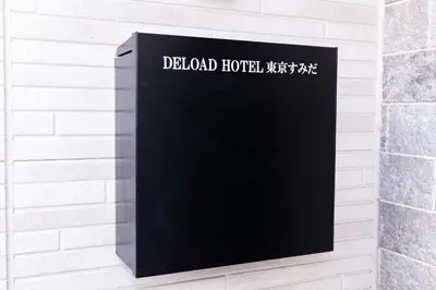 a black sign on a white brick wall at Deload Hotel \u6771\u4eac\u3059\u307f\u3060 in Tokyo