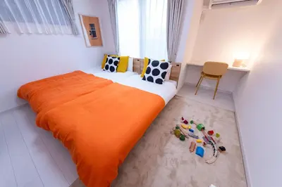 a bedroom with a large bed with an orange blanket at VicoloHouse\u5343\u4f4f\u5927\u6a4b,Family Friendly New House,Near Skytree,12 Guests in Tokyo