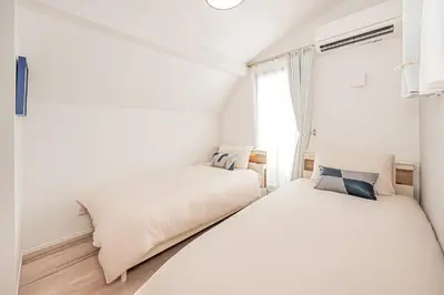 two beds in a white room with a window at Minami Inn 3 bed rooms Villa 8 minutes walk from JR line Koiwa station For Family in Tokyo