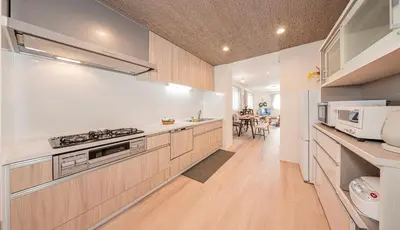 a kitchen with white walls and wooden cabinets at Minami Inn 3 bed rooms Villa 8 minutes walk from JR line Koiwa station For Family in Tokyo