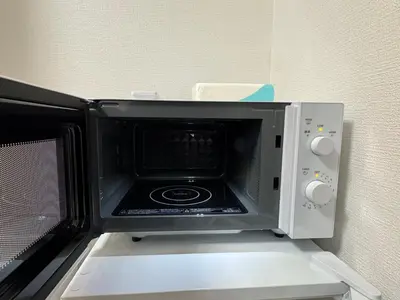 a microwave oven with its door open on a shelf at 15 min to Shinjuku, 4 min walk to nearest station, quiet brand-new residence in Tokyo