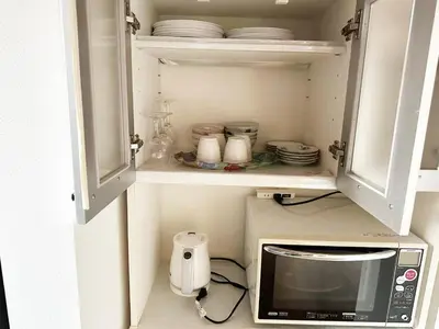 a kitchen with a microwave and some dishes at \u56db\u4eba\u90e8\u5c4b\u30d5\u30a1\u30df\u30ea\u30fc\u30bf\u30a4\u30d7 in Tokyo
