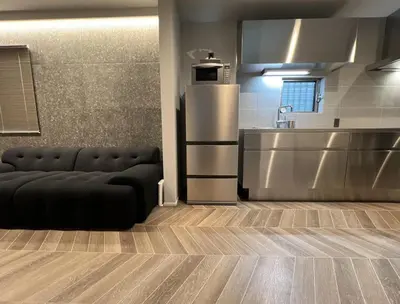 a black couch in a kitchen with a refrigerator at Koenji Designer house 50m2, 5min to Shinjuku in Tokyo