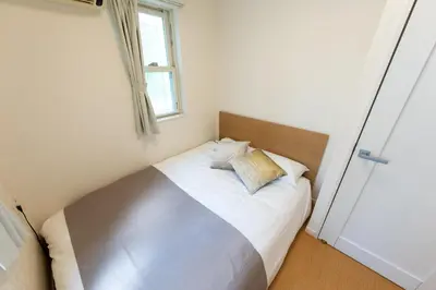 a bed in a small room with a window at Mic House SHINJUKU in Tokyo