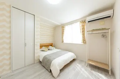 a white bedroom with a bed and a window at Mic House SHINJUKU in Tokyo