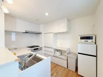 a white kitchen with a sink and a refrigerator at 5 min to JR Tabata Station Entire 3BR House 82sqm Sleeps 5 Hot Tub Newly Built in Tokyo