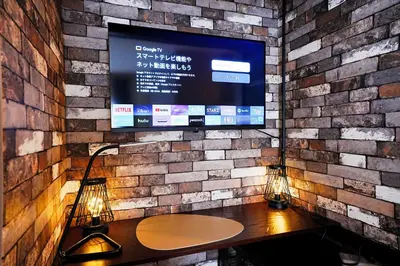 a tv on a brick wall with a table and two lamps at Clair US Tokyo in Tokyo