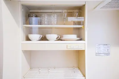 a cupboard with bowls and dishes in it at Clair US Tokyo in Tokyo