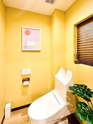 a yellow bathroom with a toilet and a plant at Astra house in Tokyo