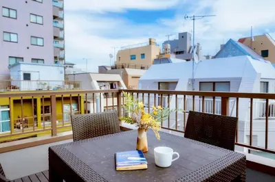 a table with a vase of flowers on a balcony at Astra house in Tokyo