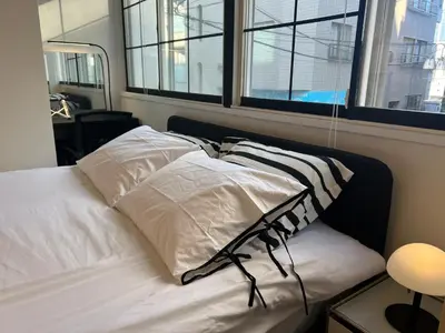 a bed with three pillows on it in a room with windows at Kuro House - In the middle of Hiro, Omotesando, Roppongi in Tokyo