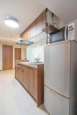 a kitchen with a white refrigerator and wooden cabinets at \u68ee\u4e0b\u30ad\u30fc\u30b3\u30fc\u30dd\u30db\u30c6\u30eb\u6700\u59278\u540d\u5bbf\u6cca\u53ef\u80fd in Tokyo