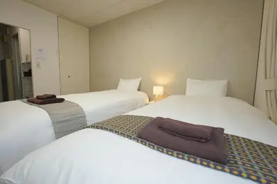 two beds in a hotel room with white sheets at INA HOUSE Koiwa 202 in Tokyo