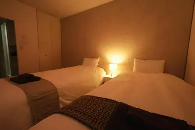 a room with two beds and a light on the wall at INA HOUSE Koiwa 202 in Tokyo